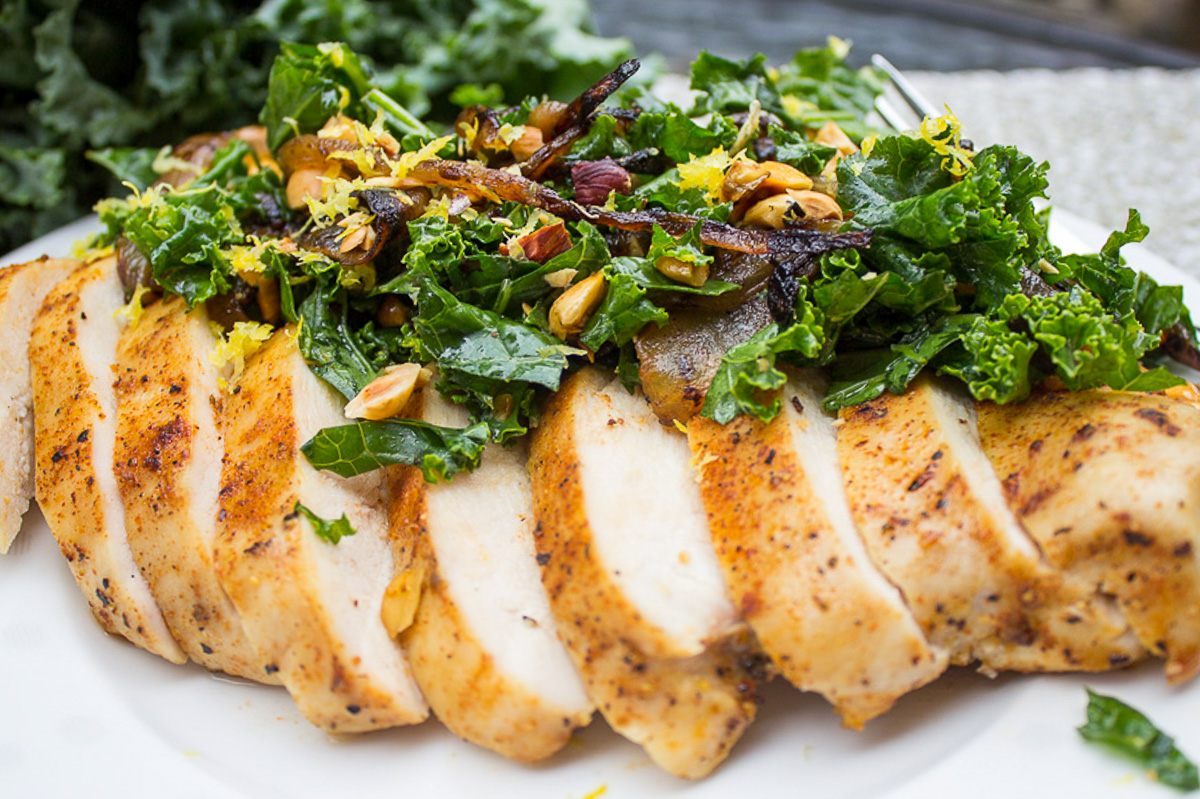 kale slaw topping a sliced cooked chicken breast on a plate.