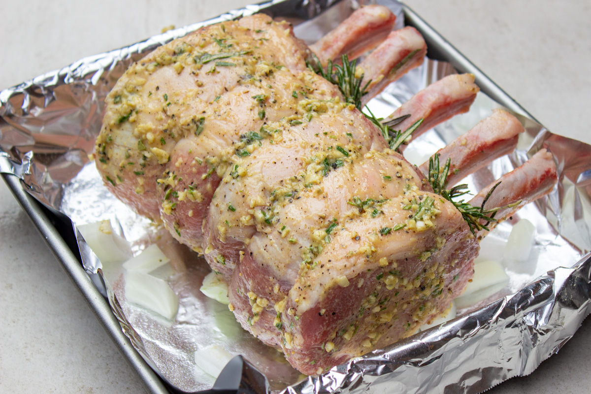 seasoned rack of pork in roasting pan before cooking. 