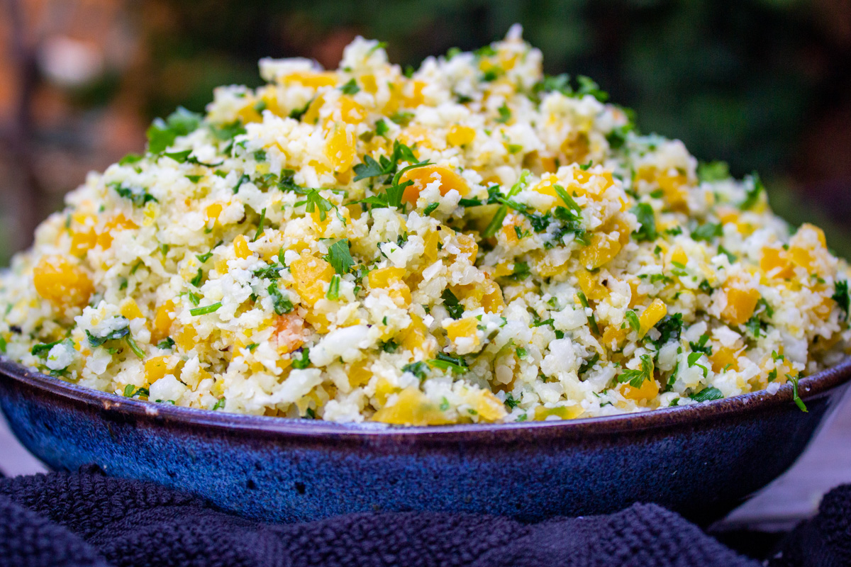 bowl of seasoned cauliflower rice and butternut squash on table.