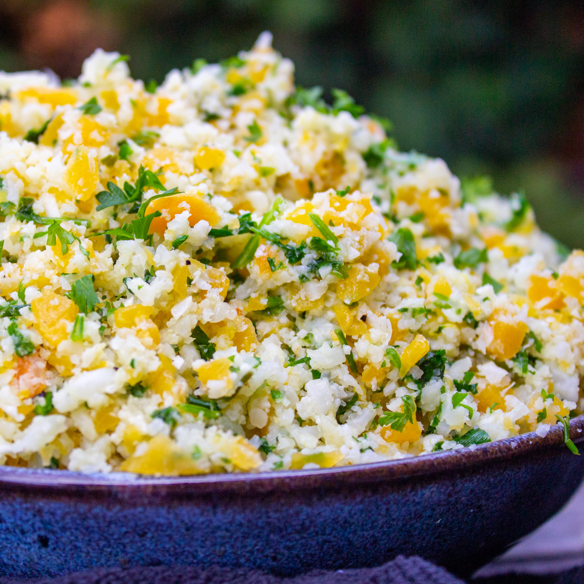 bowl of seasoned cauliflower rice and butternut squash on table.