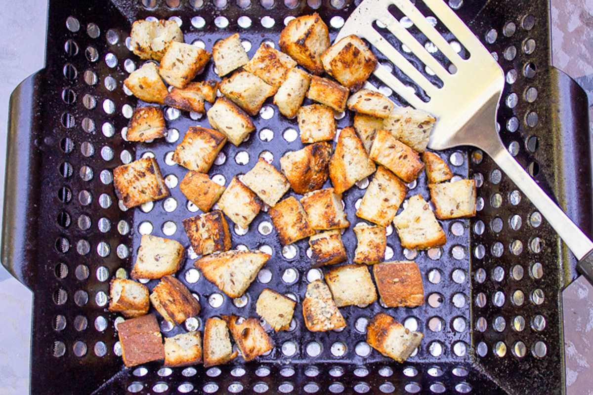 bread cubes grilling in grill basket.