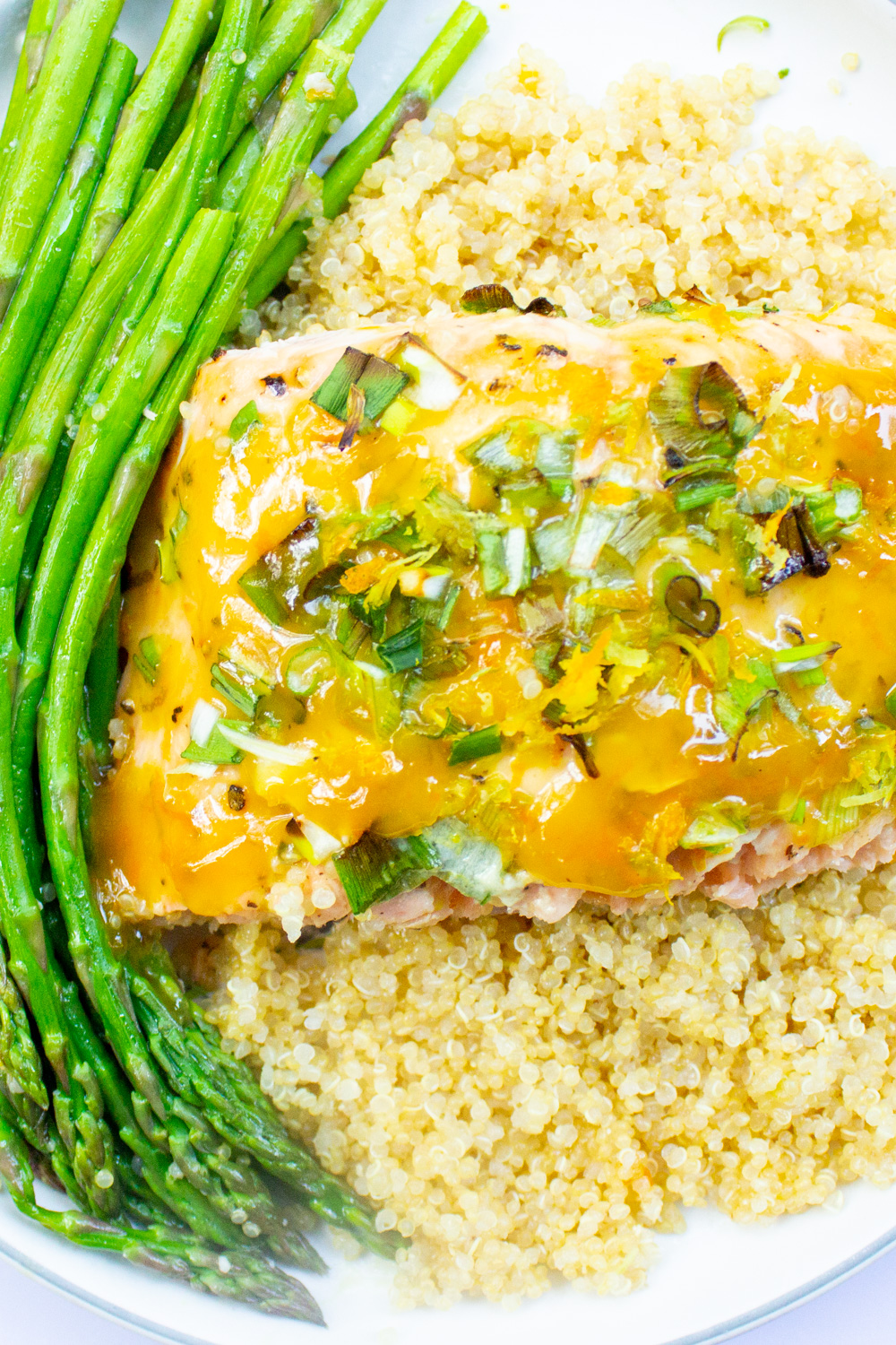 baked citrus salmon over quinoa with asparagus on plate.