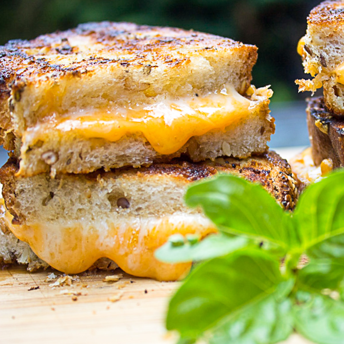 two oozing stacked grilled cheese sandwiches on cutting board. 