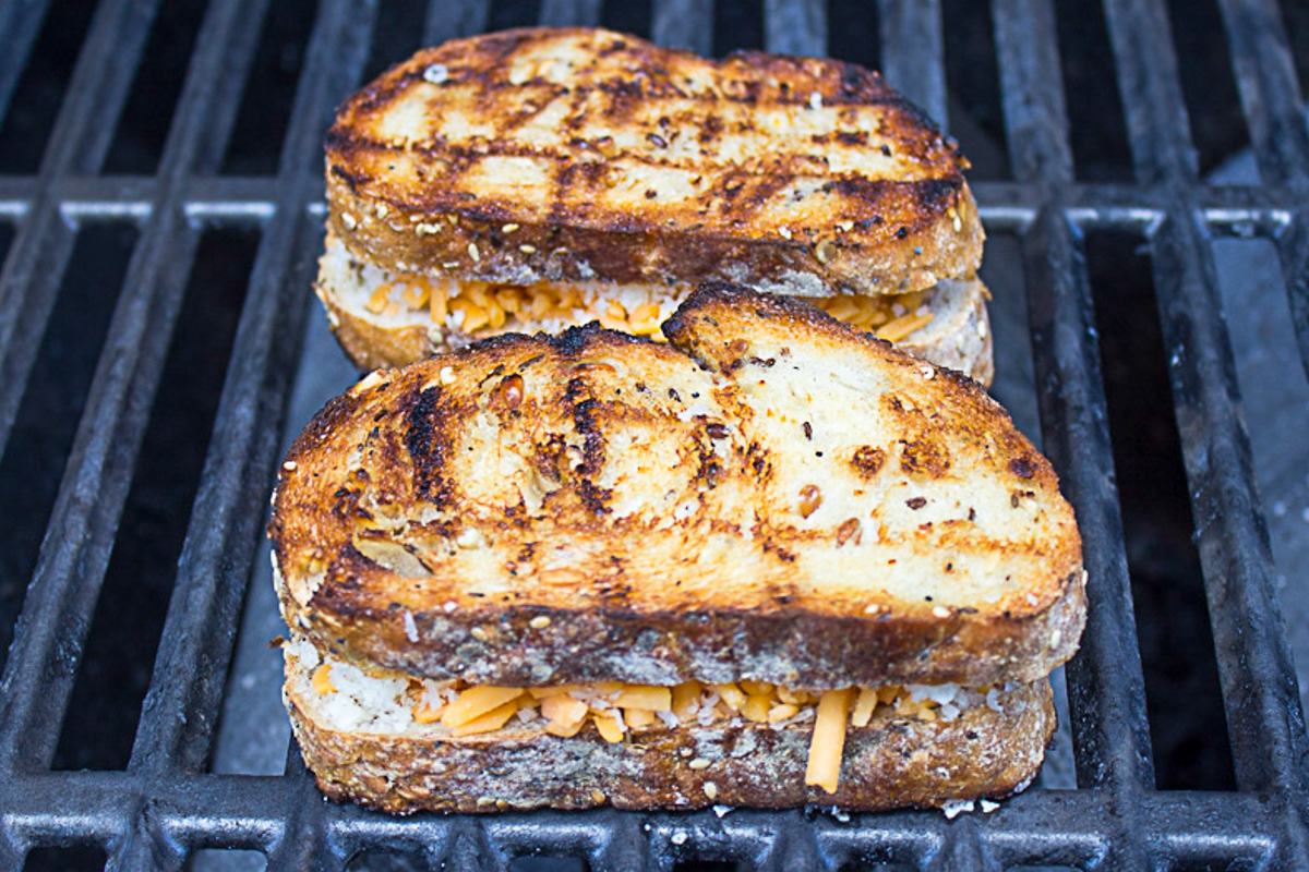 two grilled cheese sandwiches on grill.