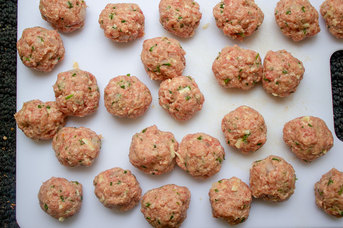 meatballs uncooked on lined baking pan.