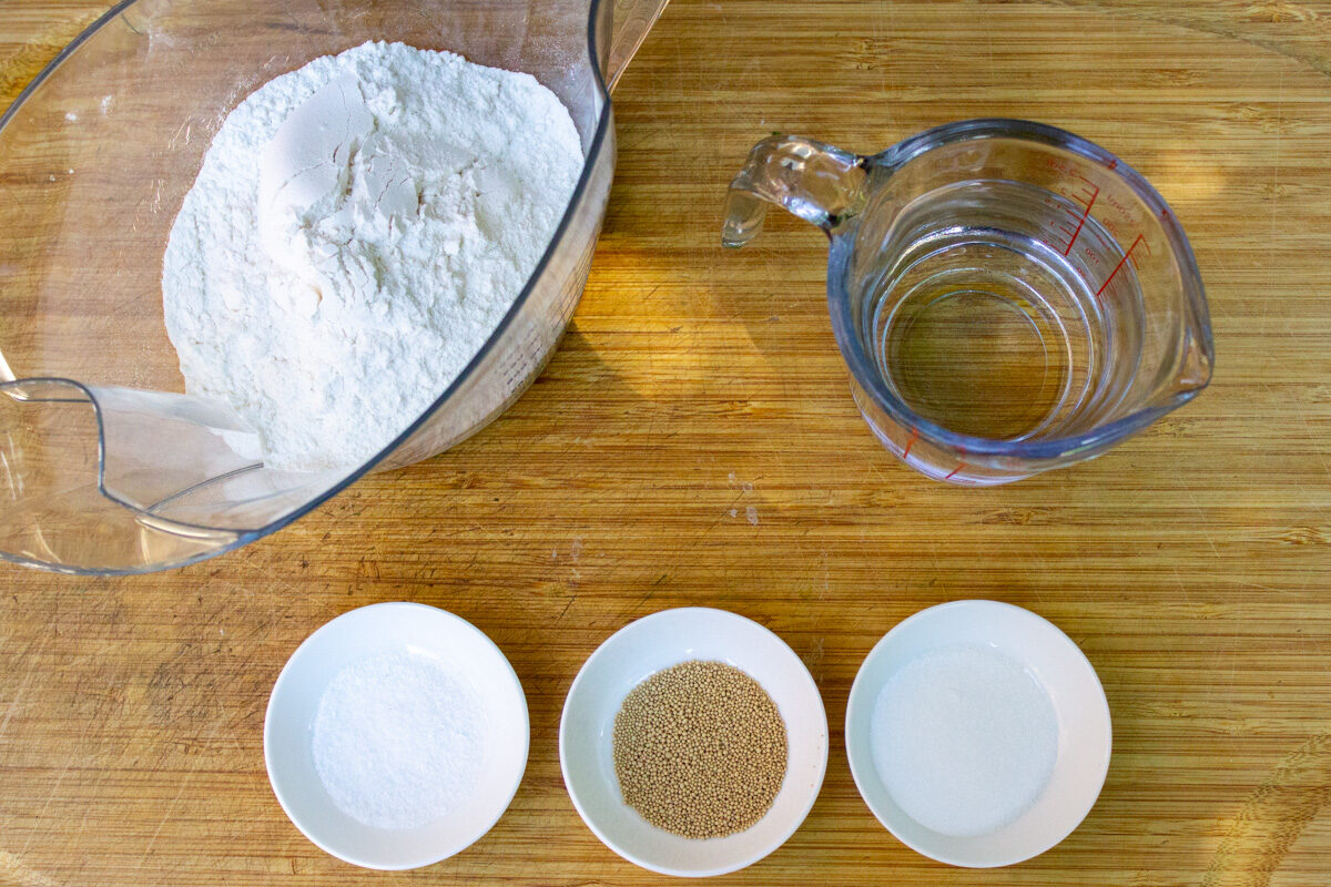 yeast, salt, sugar, water, flour on cutting board.