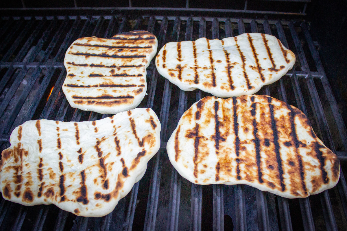 4 grilled naan on grill.