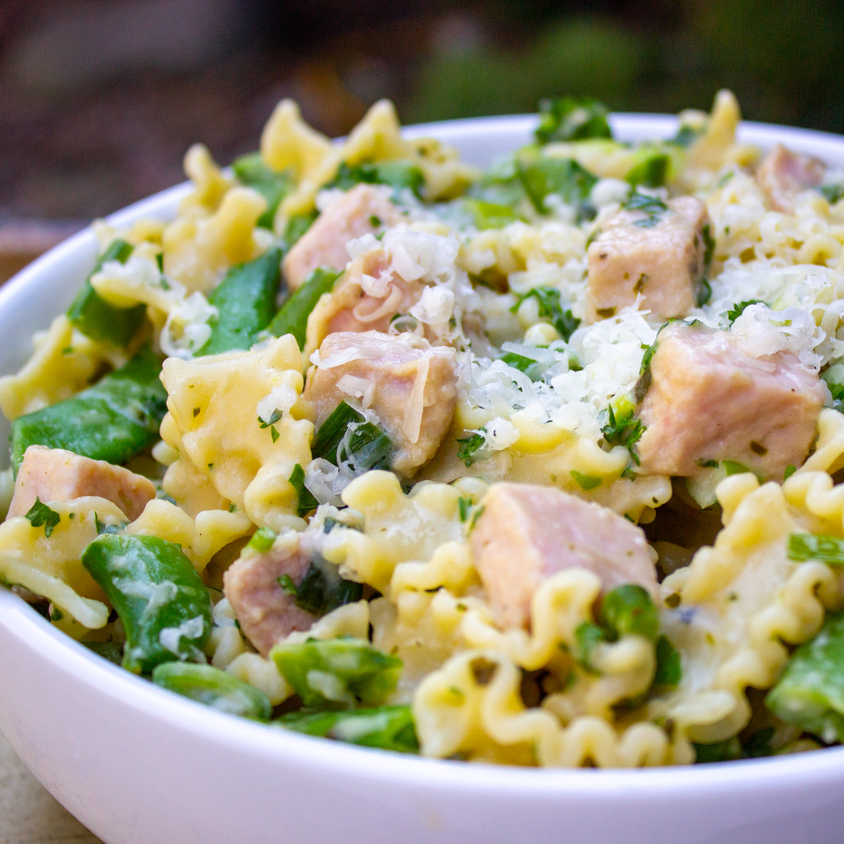 creamy pasta with peas and ham in bowl.