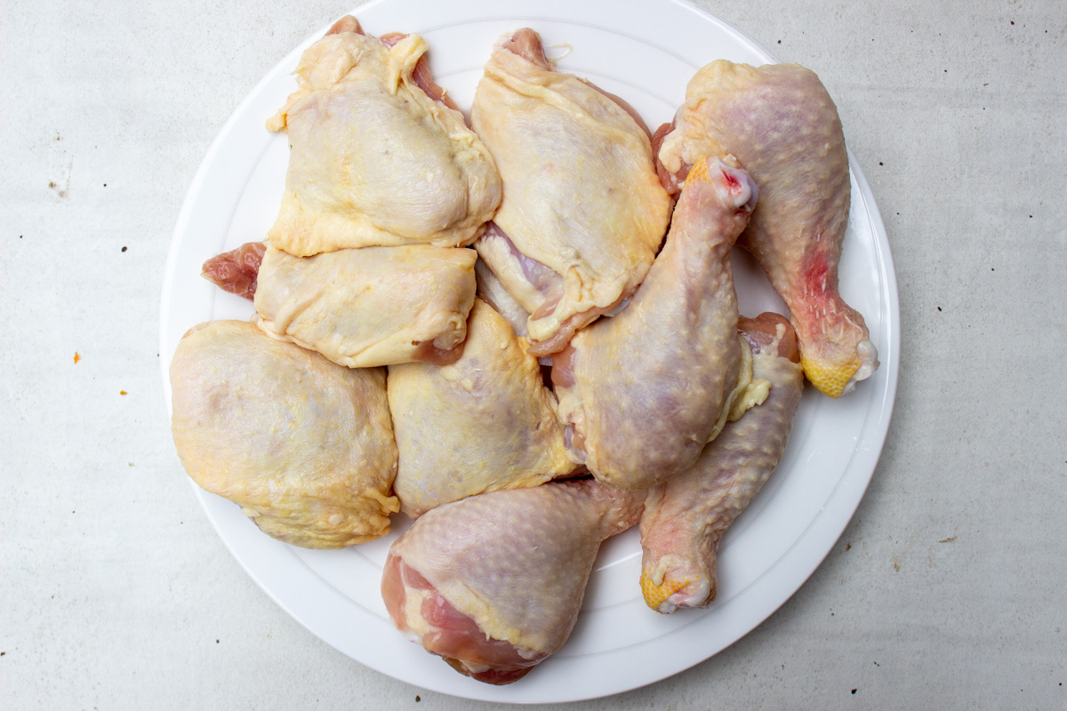 raw chicken drumsticks and thighs on plate.