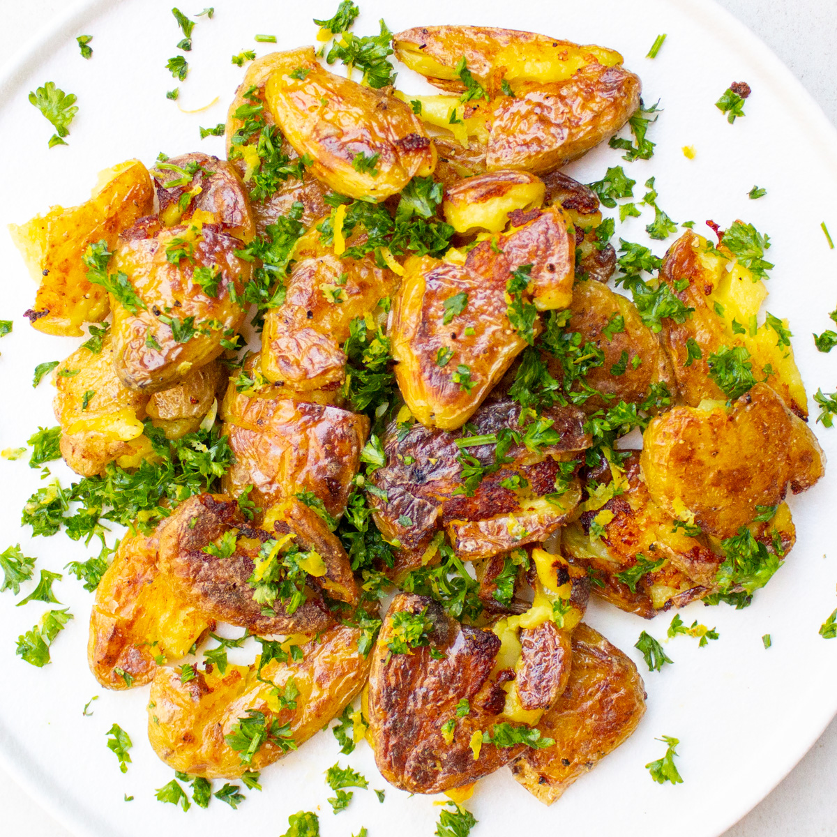 roasted smashed fingerling potatoes topped with gremolata on plate.