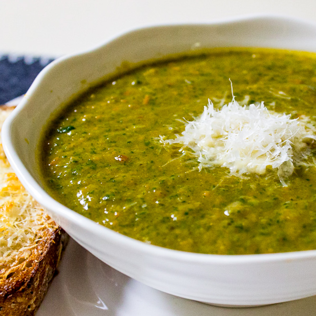 bowl of sweet potato and carrot soup with spinach topped with grated parmesan.