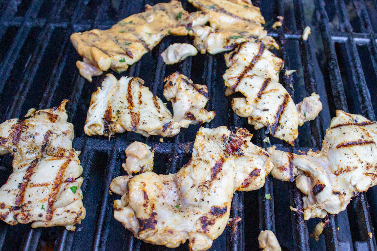 marinated chicken grilling on gas grill.