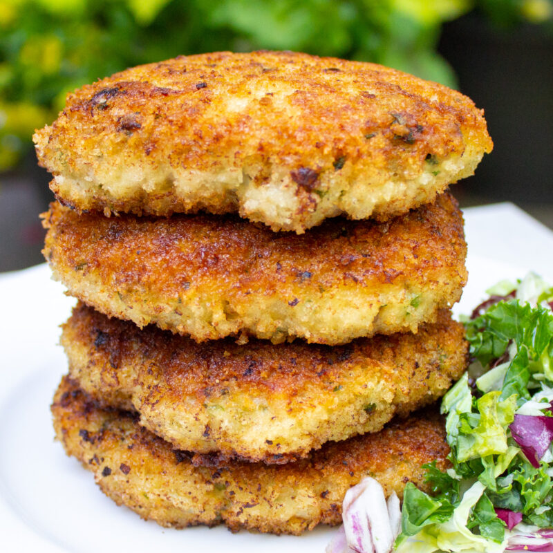 4 crispy chicken burgers stacked on a plate.