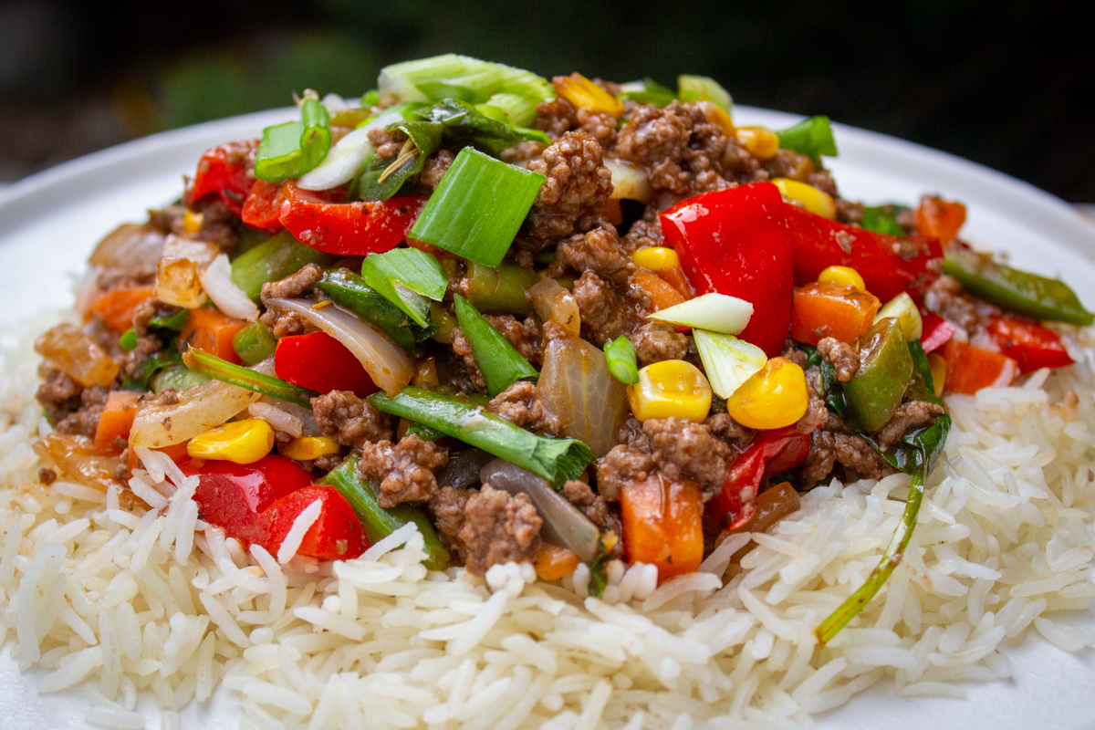 ground beef stir fry over rice on plate.