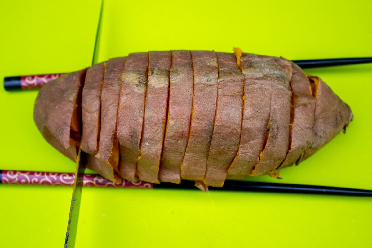 microwaved sweet potato sliced hasselback. between two chopsticks.
