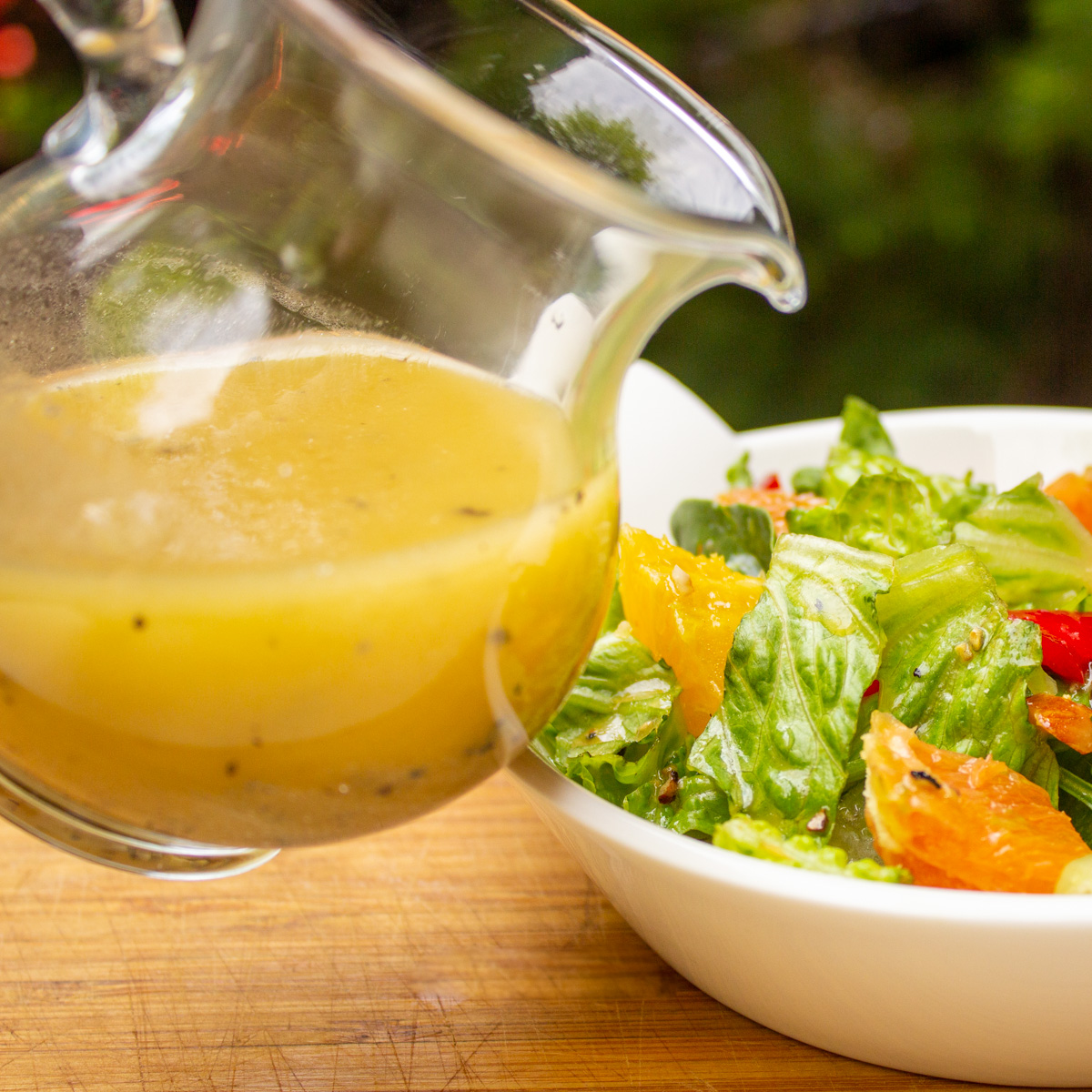 pitcher tipped over salad to pour honey lemon dressing.