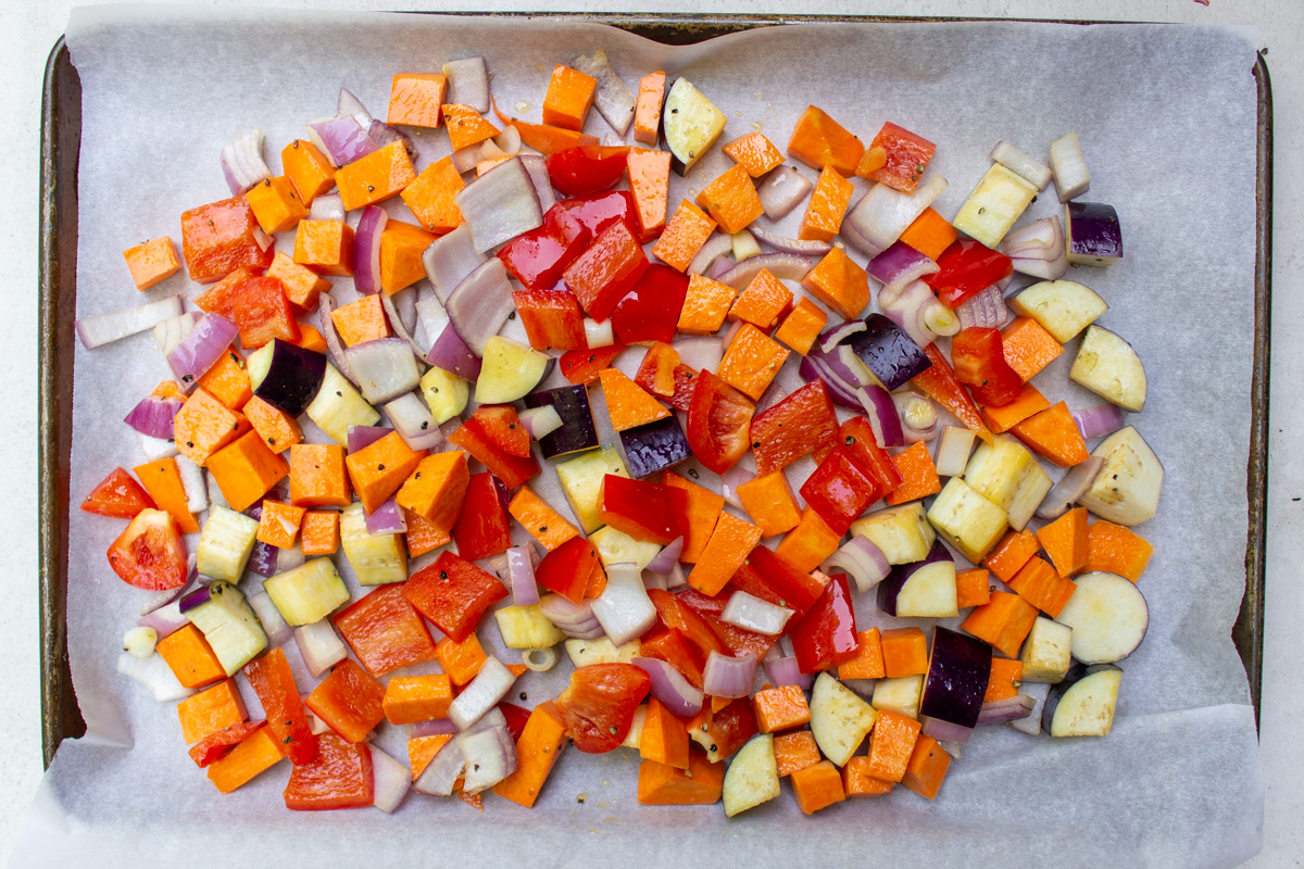 veggies laid on parchment-lined sheet pan to roast.