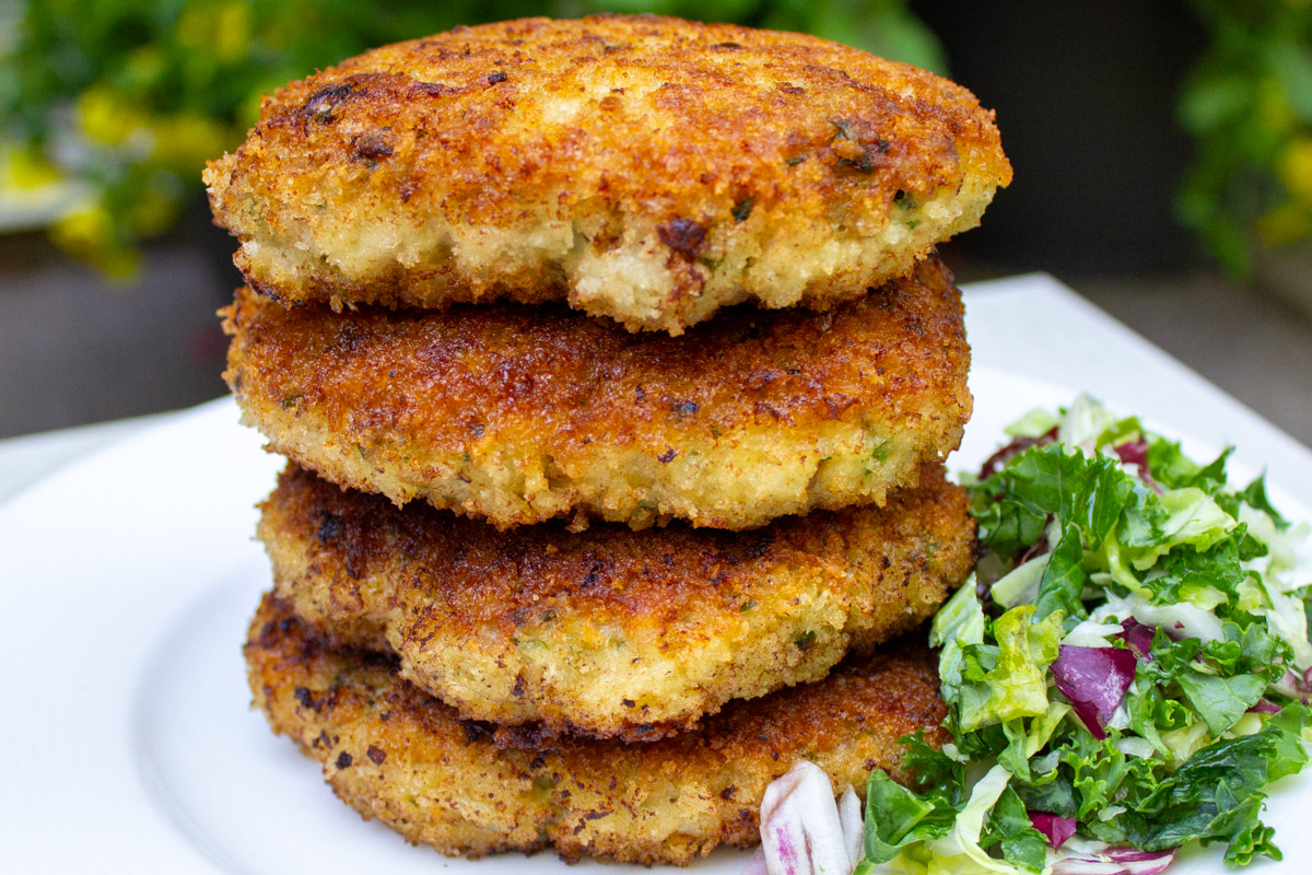 4 ground chicken burgers stacked on a plate.