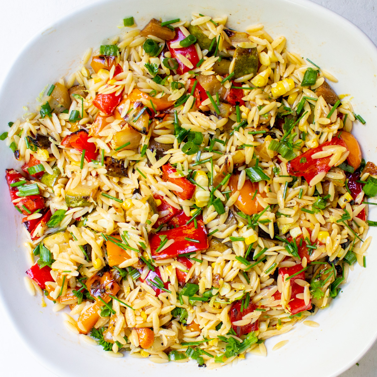 lemon orzo salad with grilled veggies in white bowl.