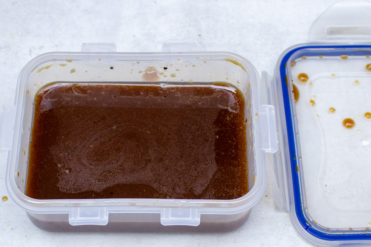 maple balsamic dressing in plastic container with lid beside it.