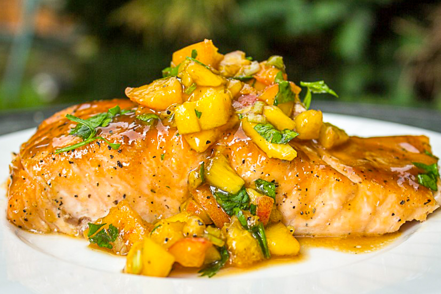 maple ginger salmon with peach salsa on top sitting on plate.