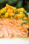 maple ginger salmon with peach salsa on top sitting on plate.