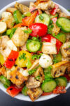 panzanella tuscana salad with grilled chicken in white bowl.