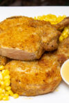 shake and baked pork chops on plate with corn and asparagus.