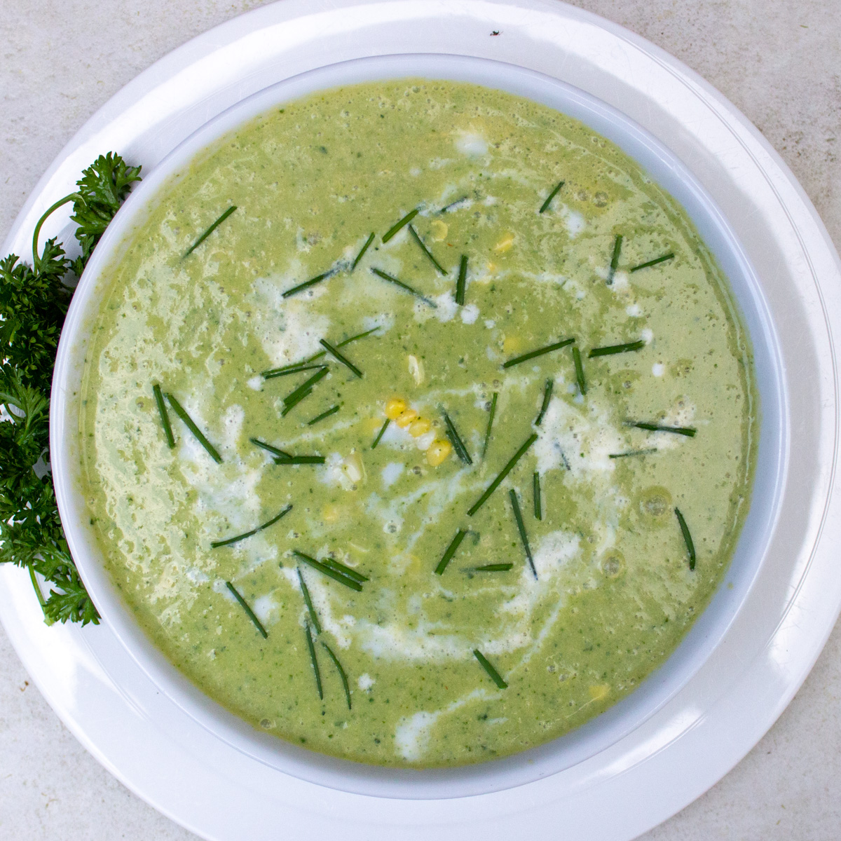 bowl of sweet corn soup with herbs, garnished.