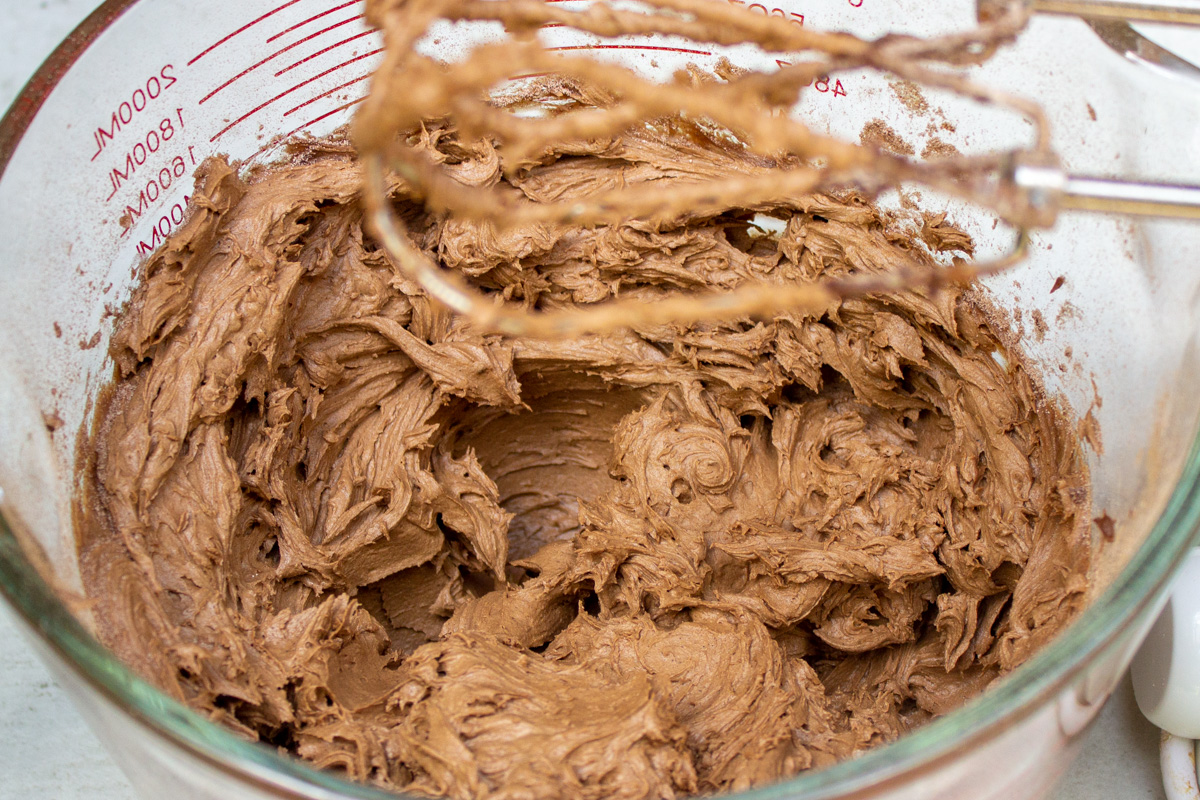chocolate buttercream icing with electric beaters over the bowl.