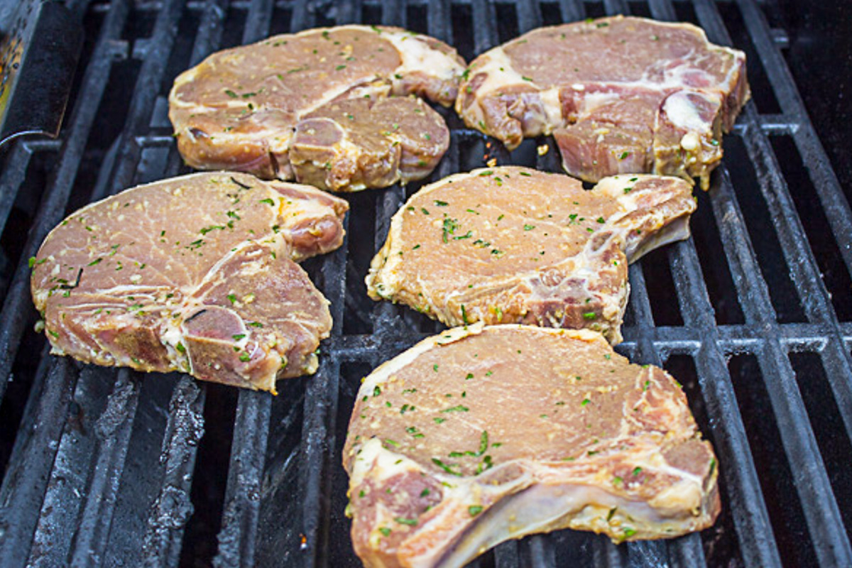 marinated pork chops cooking on grill.
