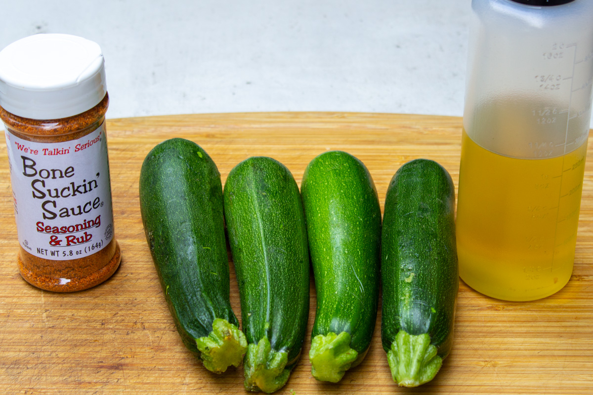 4 zucchini, olive oil, bbq dry rub on cutting board.