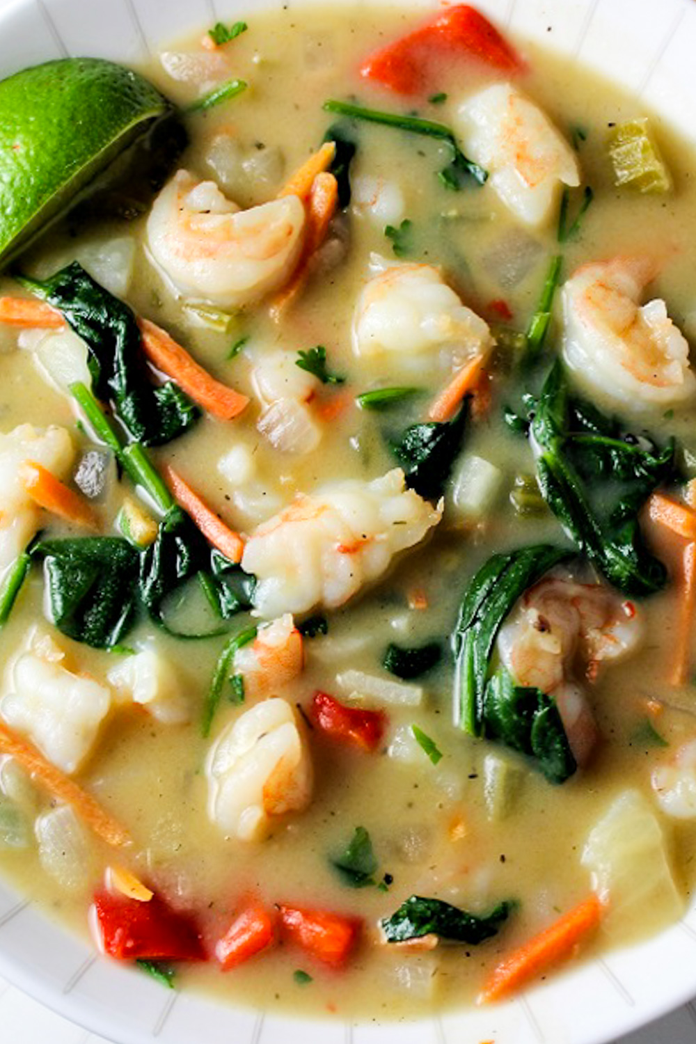 thai style shrimp soup in bowl with spinach and veggies.