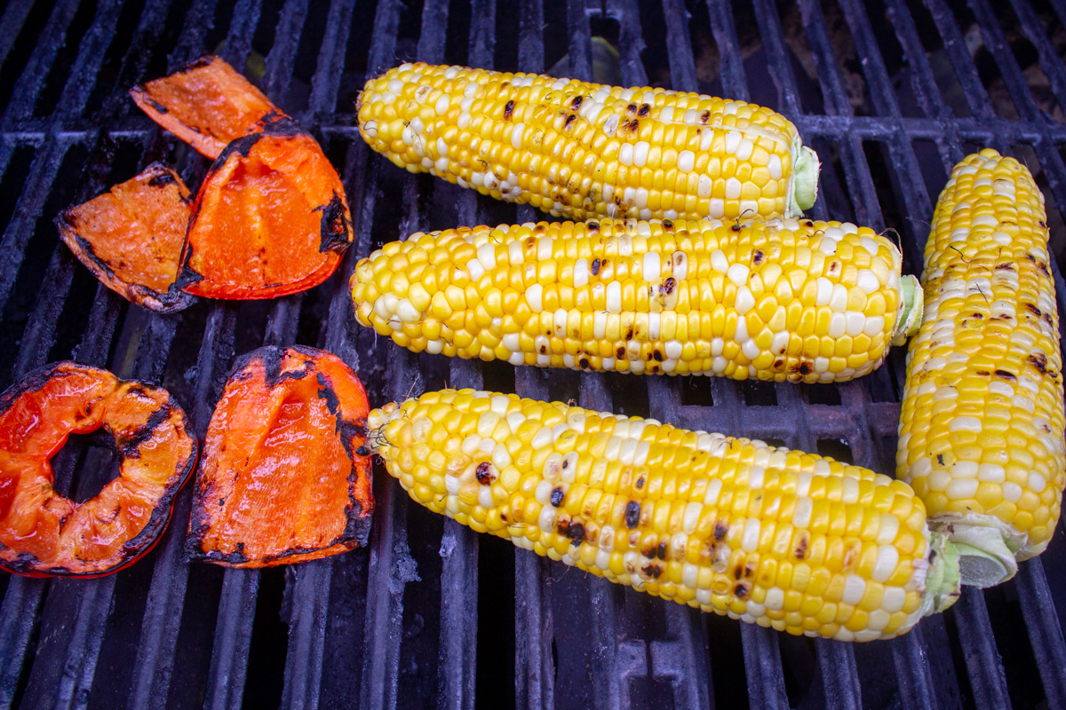 corn on cob and red bell peppers on grill.