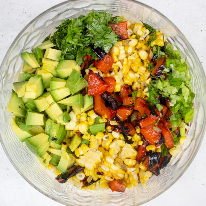 ingredients for charred corn salad assembled in glass bowl.