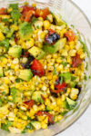 charred corn salad in a white bowl garnished with cilantro.