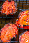 fire roasted tomatoes sitting on wire rack over baking sheet.