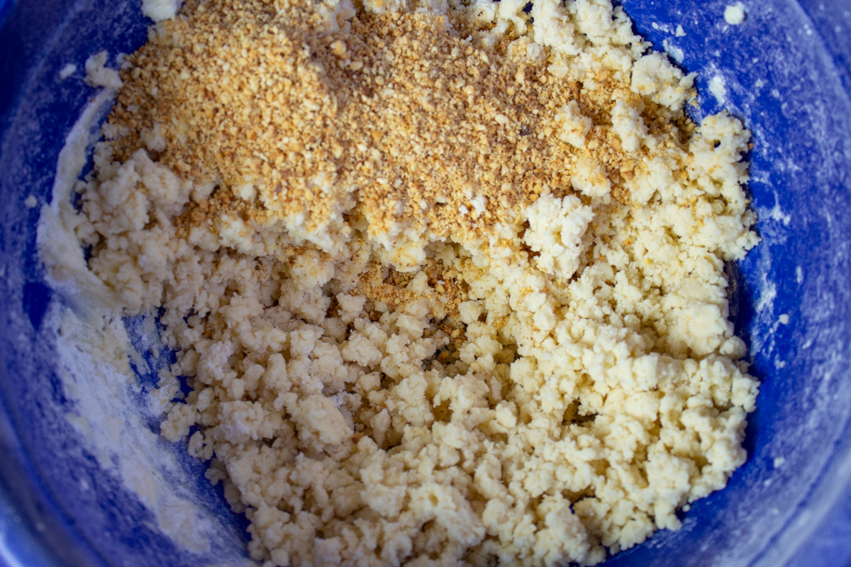 cookie dough in blue mixing bowl with crushed hazelnuts added.