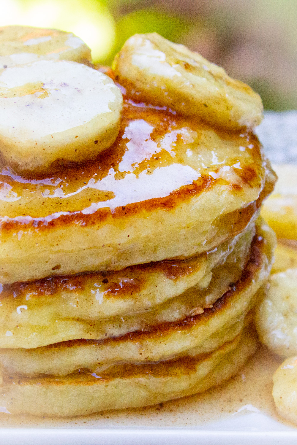 stack of ricotta pancakes with caramelized bananas on top on a plate.