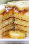 stack of ricotta pancakes cut open with caramelized bananas on top on a plate.