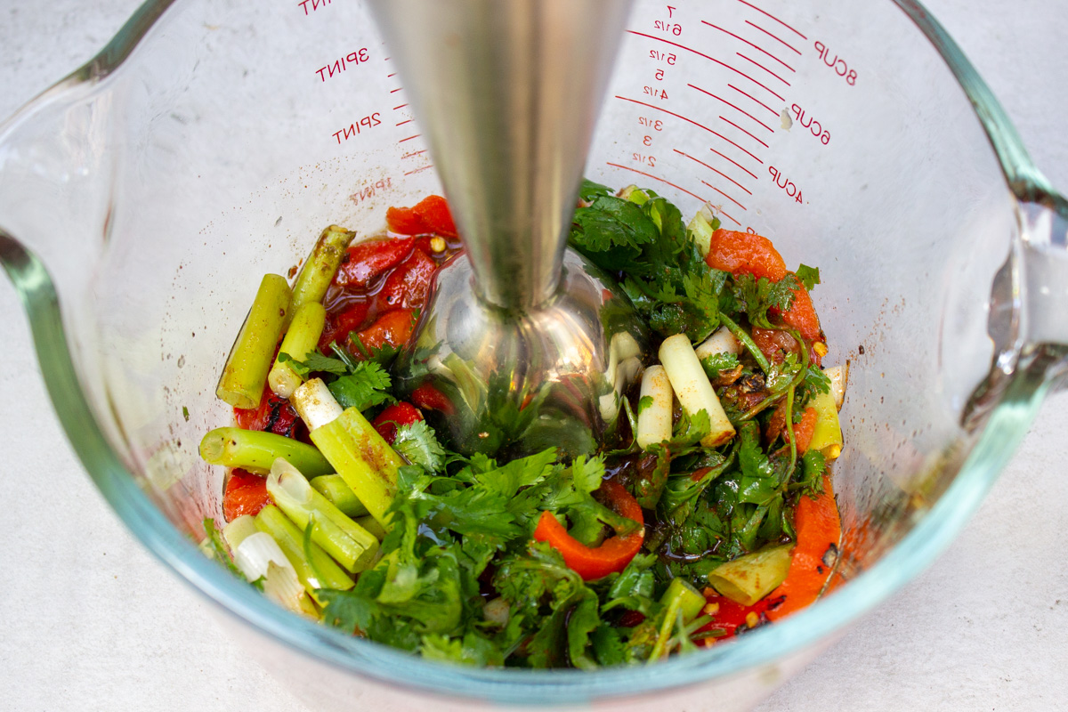 ingredients for spicy peri peri style sauce in large measuring bowl with immersion blender.