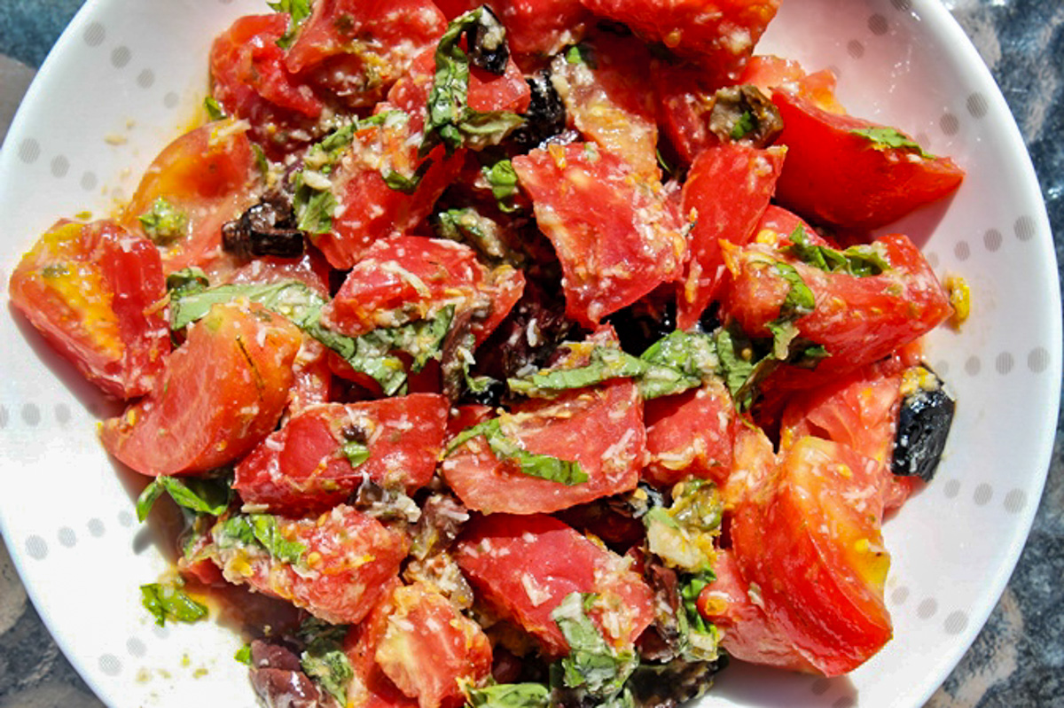 chopped tomatoes, olives, basil and cheese in bowl.