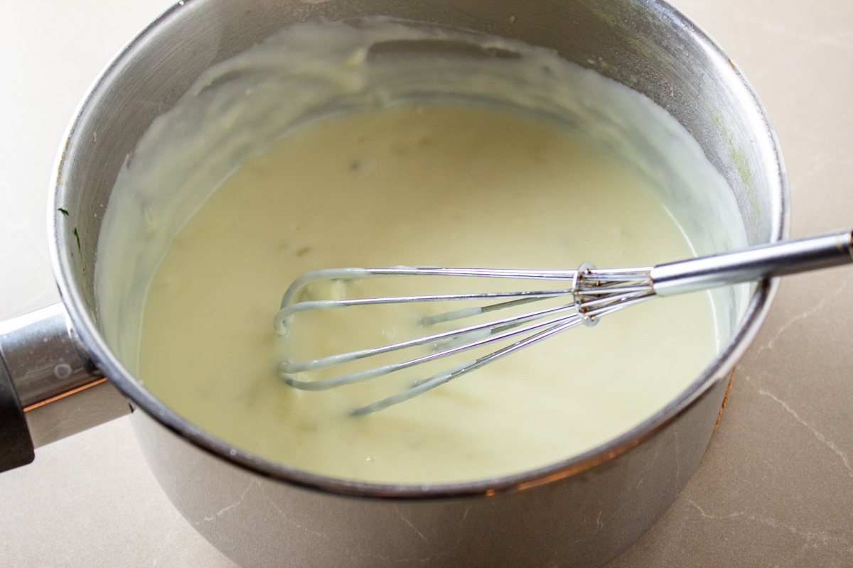 cheese sauce in pot with whisk.