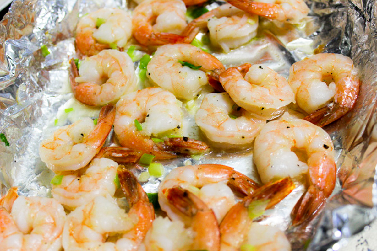 baked shrimp with seasonings on foil lined pan.