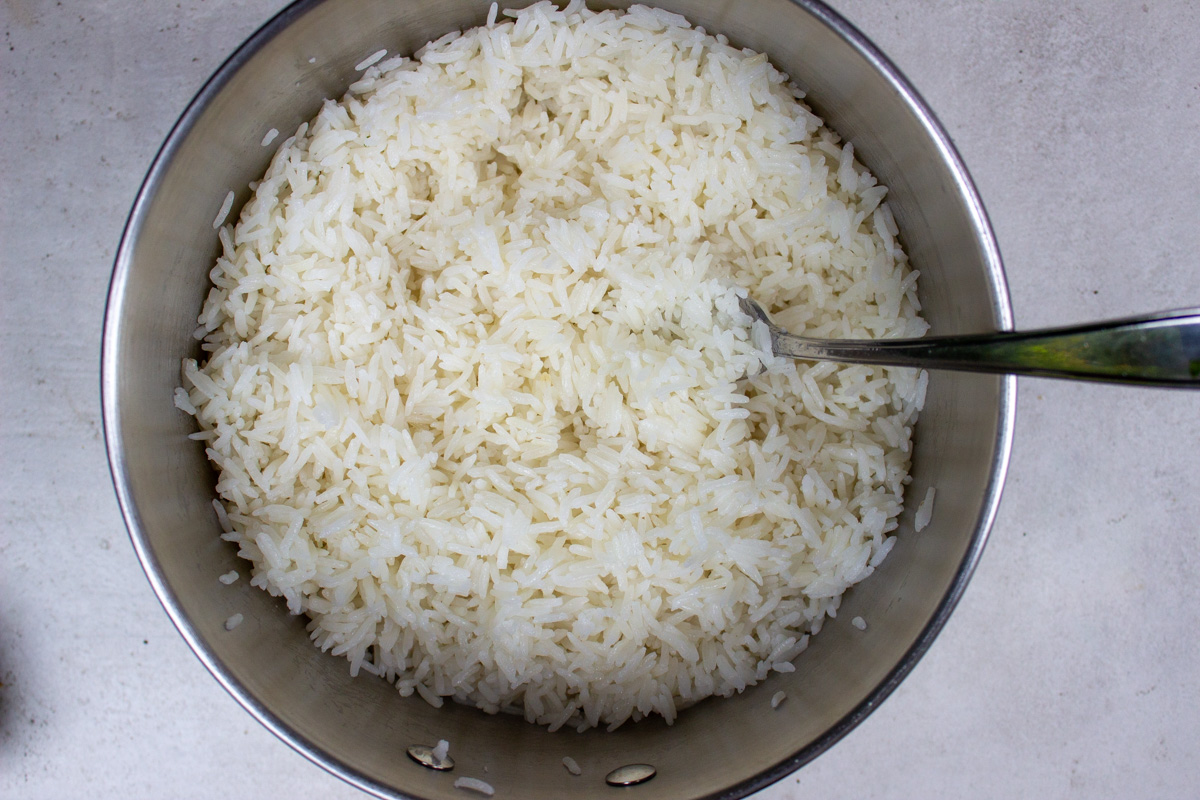 fluffing rice with fork in pot after cooking.
