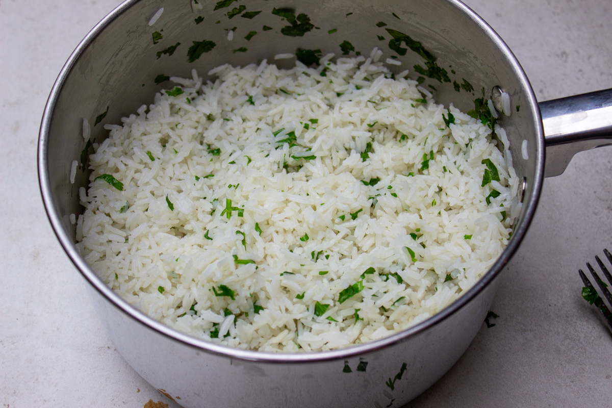 cilantro added to cooked rice in pot.