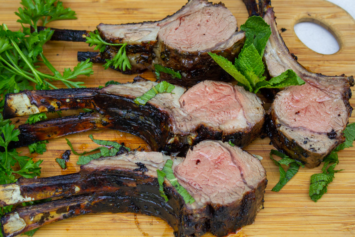 four sliced double lamb chops off rack of lamb on cutting board.