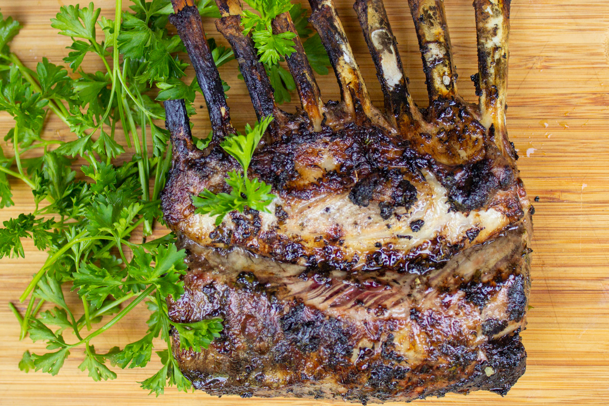 grilled rack of lamb on cutting board with parsley.