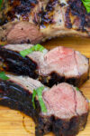 two sliced double lamb chops beside rest of rack of lamb on cutting board.