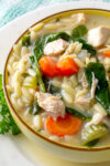 lemon orzo soup with chicken, veggies and coconut milk in yellow bowl.